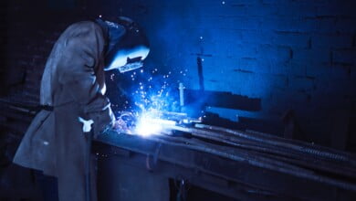 man wearing welding helmet welding metal near gray brick 1474993